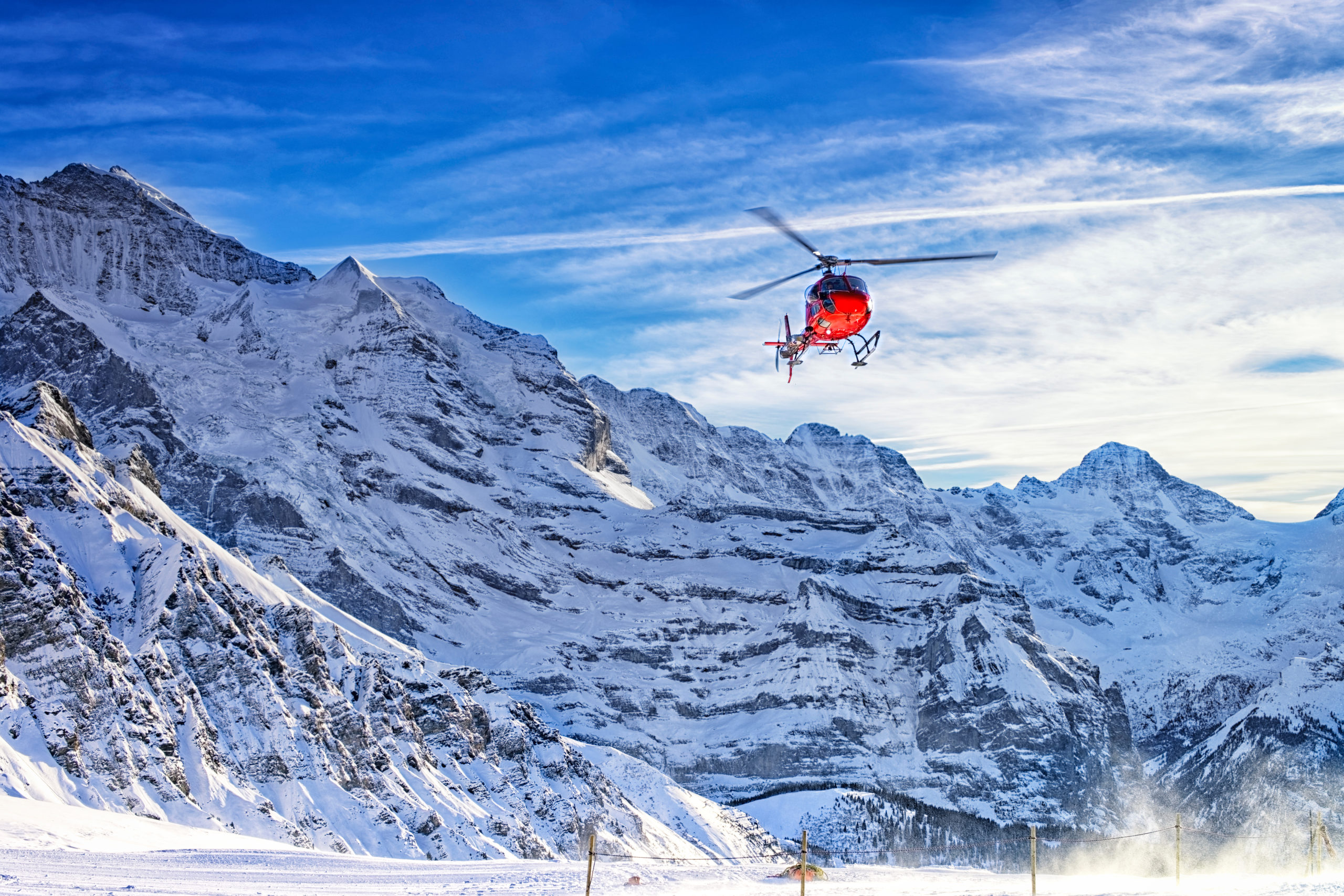 red helicopter flying at swiss alps near jungfrau mountain